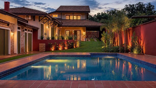 A two-story house with a swimming pool, surrounded by a well-maintained garden and a red wall. - Rancho da Vó Vera | Recém Reformado e Bem Equipado (Bariri)