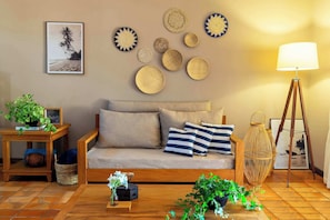 A living room with a sofa, decorative plates, a lamp, and a framed picture on the wall. - Rancho da Vó Vera | Recém Reformado e Bem Equipado (Bariri)