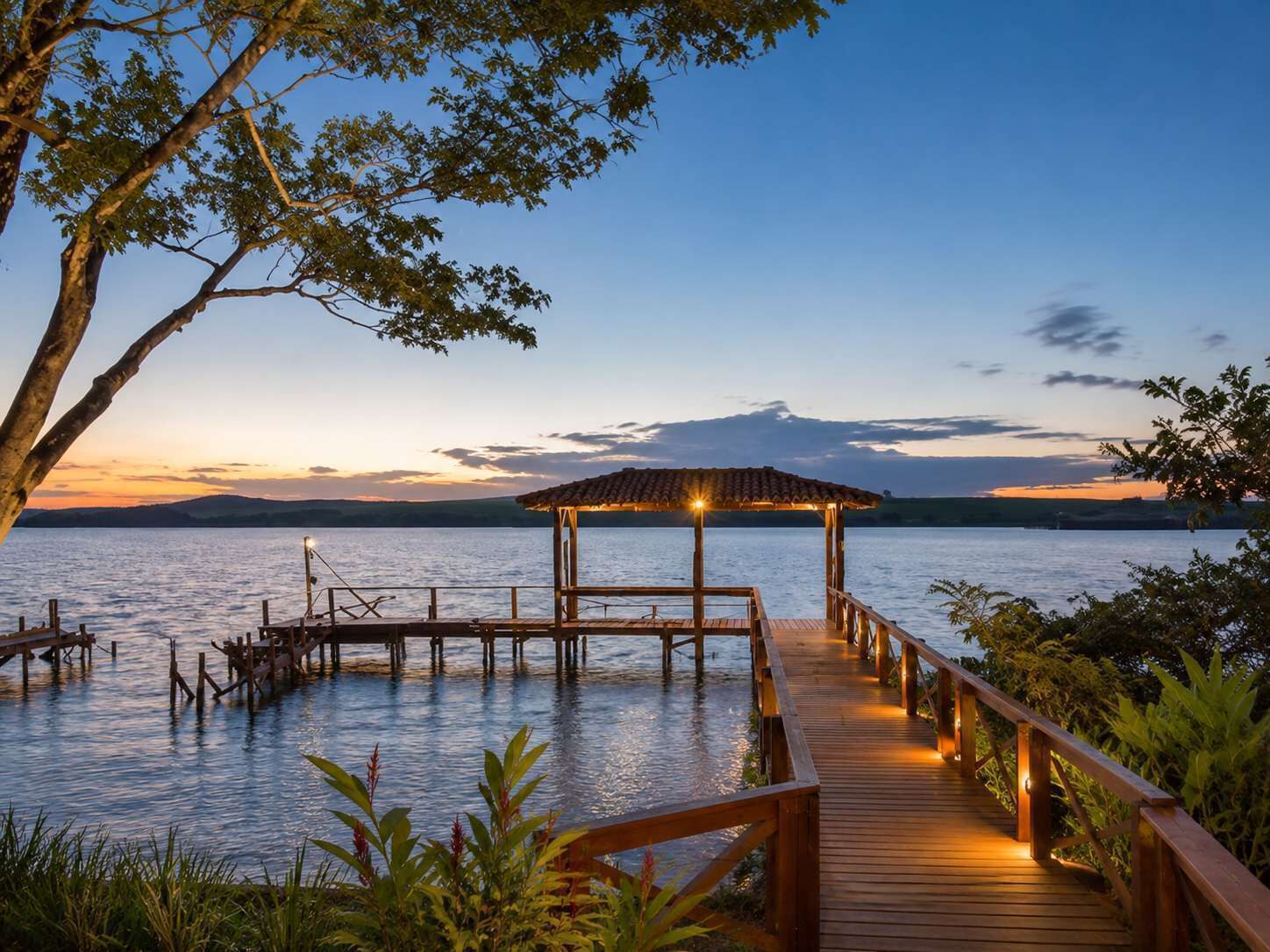 A wooden dock leading to a gazebo over water, surrounded by greenery.