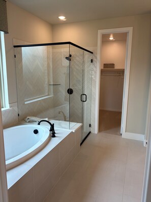 Een moderne badkamer met een glazen douchecabine, een witte wastafel en een inloopkast.