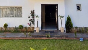 Une maison moderne à deux étages, dotée d’un balcon, d’une façade en pierre et d’une pelouse bien entretenue.