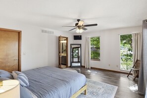 Ein Schlafzimmer mit einem Bett, einem Deckenventilator, einem Fenster und einer Tür.