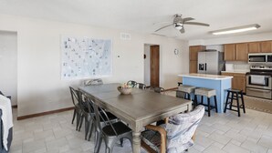 Un comedor con una mesa y sillas de madera, una cocina con electrodomésticos modernos y un ventilador de techo.