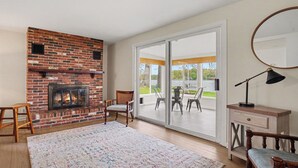 Ein Wohnzimmer mit Kamin, einer großen Schiebetür zu einer Außenpatio und einem Spiegel an der Wand.