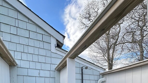 A corner of a building with white siding, a wooden bench, and a metal pipe. - Pines Cottage – Yarmouth w/ Private Beach Rights (Yarmouth)