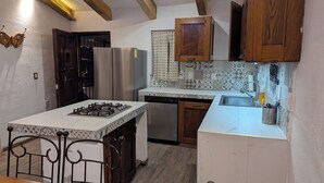 Une cuisine équipée d’une cuisinière à gaz, d’un lave-vaisselle, de meubles de rangement en bois et d’un crédence décorée.