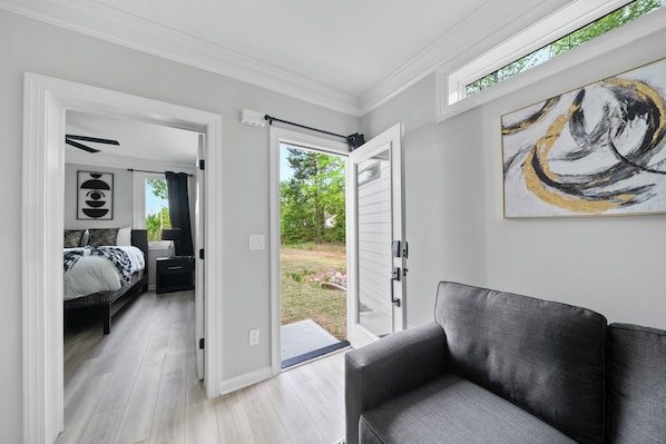 A modern interior with a bed, a gray sofa, and a large abstract painting.
