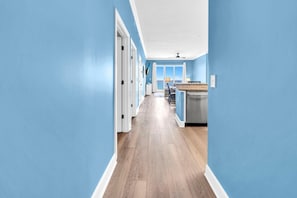 Ein Flur mit blauen Wänden, Holzdielen und einer Küchenzeile mit Arbeitsplatte und Schränken.