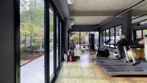 A gym with treadmills, weights, and a view of trees and buildings. - VN Alvorada (São Paulo)