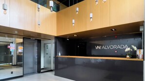 A reception desk with a black counter and a sign that reads 'ALVORADA'. - VN Alvorada (São Paulo)