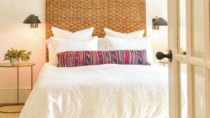 A bedroom with a wooden bed frame, white bedding, a patterned pillow, and two bedside lamps. - Suite 4 at Kubli Haus<br>Luxury, Style & Location, 1 block to Britt (Jacksonville)