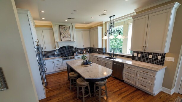 A kitchen with a central island, wooden flooring, and white cabinetry. - Marymount College Building (Salina)