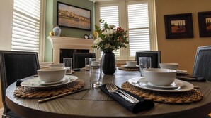 A dining table set for four with placemats, bowls, glasses, and a vase of flowers. - Marymount College Building (Salina)