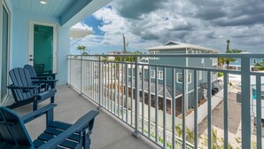 A balcony with chairs, a ceiling fan, and a view of neighboring houses. - Beach Please (Fort Myers Beach)