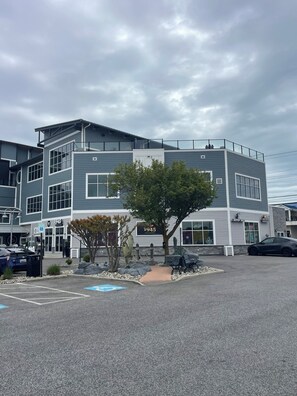 A multi-story building with a parking lot in front, a tree, and a sign that reads '1945.' - Cute 1-bedroom apt 23rd St in Ocean City near the beach (Ocean City)