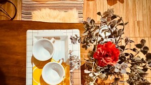 Une table sur laquelle se trouve un plateau avec des tasses et une assiette, un vase rempli de fleurs et un plaid en fourrure posé sur un plancher en bois.