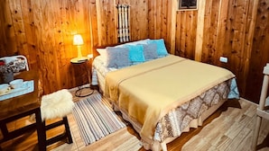 Une chambre dans une cabane en bois, avec un lit, une table de chevet, une chaise et une lampe.