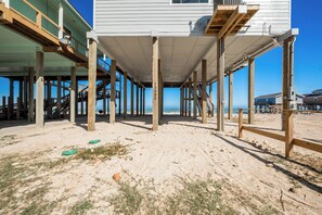 En bygning ved stranden med en træterrasse, synlige trapper og kig til havet.