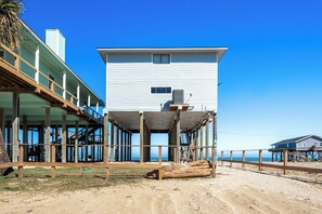 Un immeuble situé en bord de mer, doté d’un balcon, d’un escalier et offrant une vue sur l’océan.