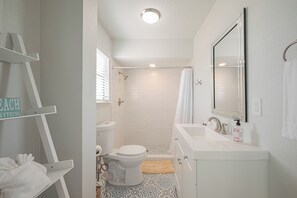 Une salle de bain comprenant des toilettes, une douche, un lavabo et un porte-serviettes.