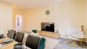 A modern living room with a dining area, a flat-screen TV, and a small side table. - Contractor and Business Stays | Sleeps 6 | WiFi (Hertfordshire)