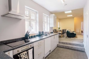 A modern kitchen with white cabinets, a black countertop, and a dining area with a sofa and table.