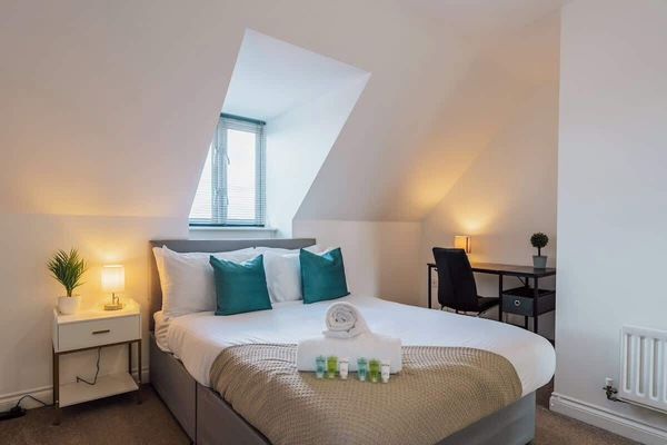 Bright attic bedroom featuring skylight, workspace, and calming decor accents