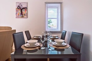 A dining table set with plates, glasses, and cutlery, with a window and blinds in the background. - Contractor-Hub Home | Close to MK & M1 (Wolverton)