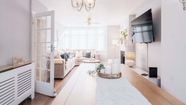 Ein modernes Wohnzimmer mit einer Couch, einem Couchtisch und einem an der Wand befestigten Flachbildfernseher.