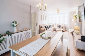Ein modernes Wohnzimmer mit einem Holzesstisch, einer Sofagarnitur und einer Chandeliebre.