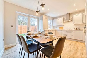 A modern kitchen with white cabinets, a wooden dining table, and black chairs. - Professionals & Families, Central, FREE Parking (West Midlands)