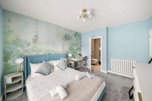 A bedroom with a bed, a desk, a chair, a radiator, and a door leading to another room. - Sleeps 6 | Relocation & Long Stays, FREE Parking (Greater London)