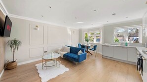 A modern living room with a blue sofa, a round coffee table, and a white rug. - Contractor Friendly 3BR | Driveway Parking | WiFi (Greater London)