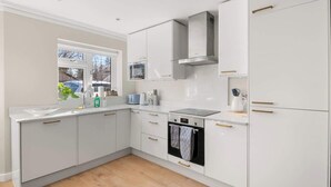 A modern kitchen with white cabinetry, a built-in oven, and a window. - Contractor Friendly 3BR | Driveway Parking | WiFi (Greater London)