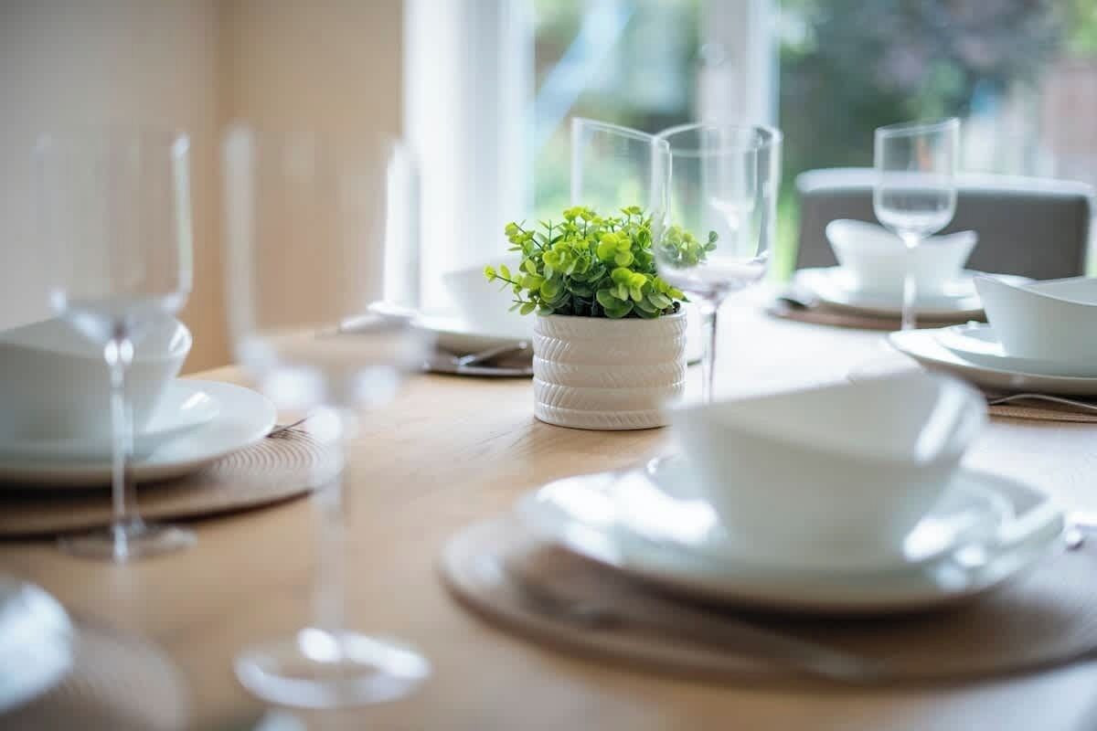 Close-up table setting with cups, greenery, and soft daylight glow

