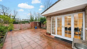 Une terrasse avec un sol carrelé, une clôture en bois et une structure en briques.