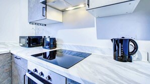 Une cuisine moderne dotée d’un four à micro-ondes, d’un grille-pain et d’une bouilloire encastrés, le tout installé sur un plan de travail blanc.