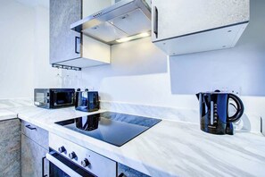 Una cocina moderna con microondas integrado, tostadora y hervidor sobre una encimera blanca.