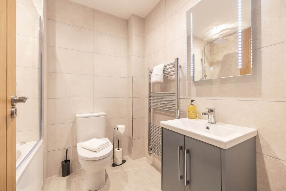 A modern bathroom with a toilet, sink, and mirror.