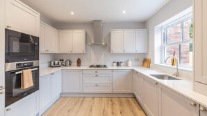 Une cuisine moderne avec des armoires blanches, un four encastré, un four à micro-ondes et une fenêtre donnant sur l’extérieur.