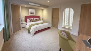 A bedroom with a bed, bedside tables, a desk with a laptop, and a window with a view. - Modern Hotel Room In Historic Malthouse (Newport)