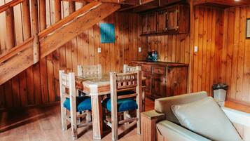 Un interior de madera con una mesa y sillas de comedor, un sofá y una zona de kitchenette.