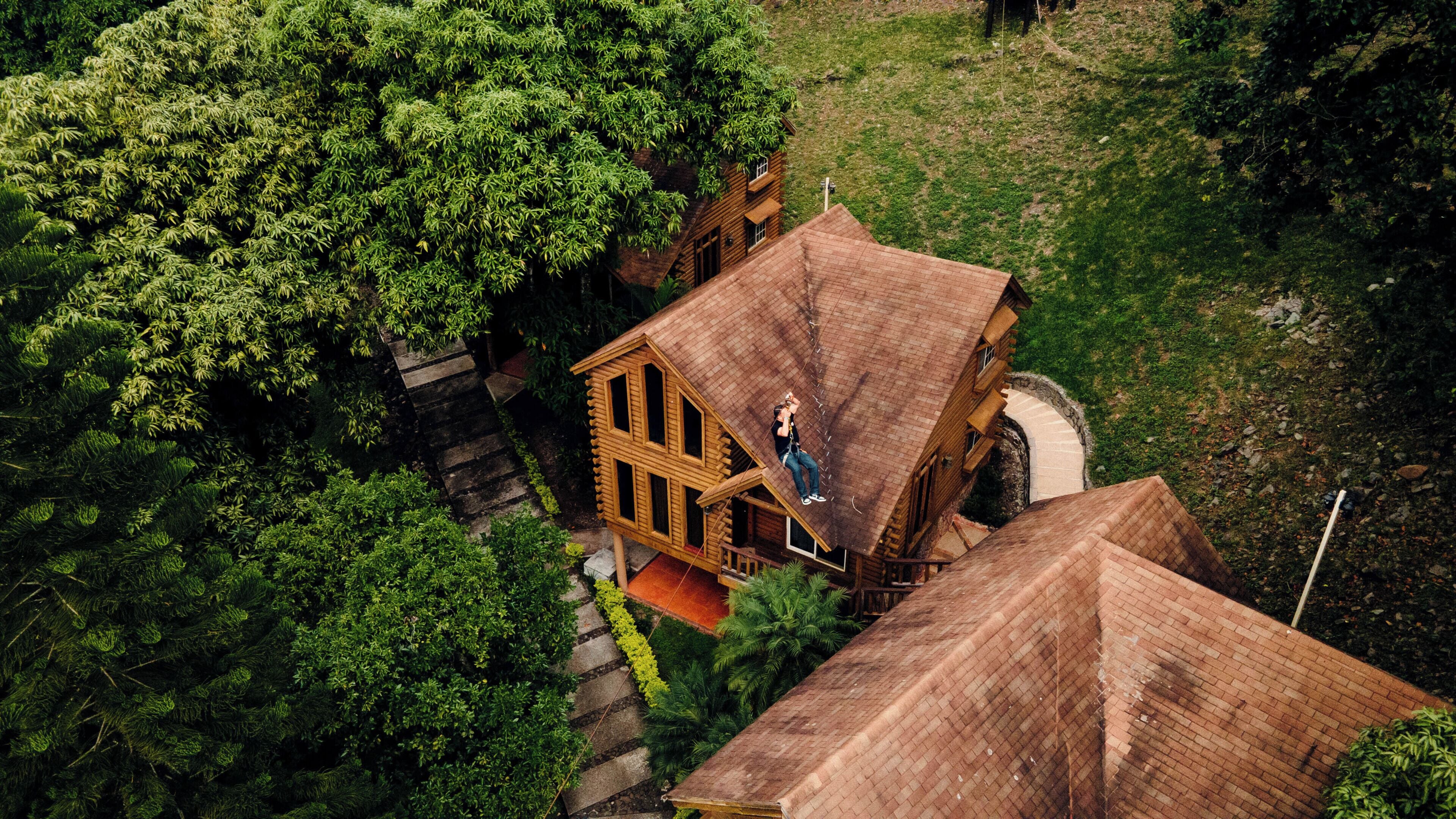 A wooden house with a steep roof, surrounded by dense greenery.