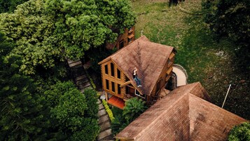 A wooden house with a steep roof, surrounded by dense greenery.