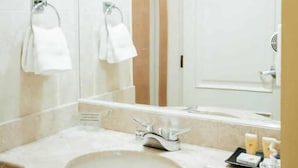 Un baño con un espejo grande, un lavamanos y dos barras para toallas.
