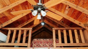Un interior de madera con ventilador de techo, alfombra estampada y barandilla de madera.