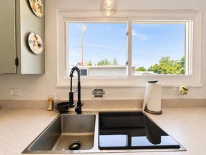 A kitchen with a double sink, a window, and a view of the outside.