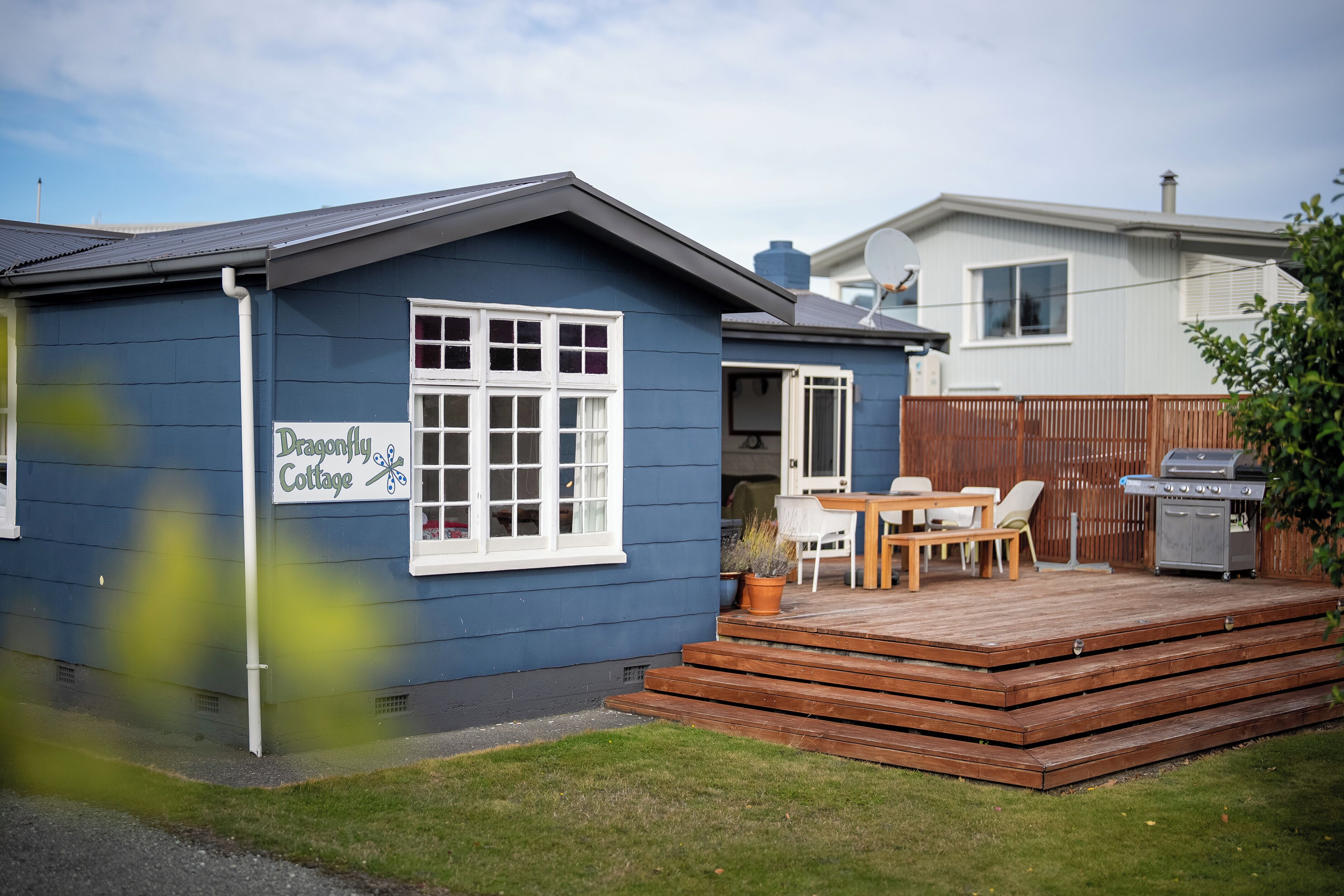 Una cabaña azul con terraza, una barbacoa y un letrero que dice 'Dancing Cottage'.