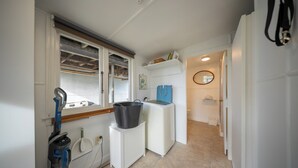 Pieni keittiö, jossa on ikkuna, sisäänrakennettu pesukone, pieni kaappi ja peili.