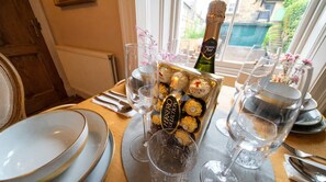 Ein gedeckter Tisch mit Tellern, Besteck, Gläsern, einer Champagnerflasche und einer Schachtel Ferrero Rocher Pralinen.